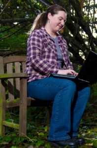 Photograph of Kate Ringland sitting on bench with laptop