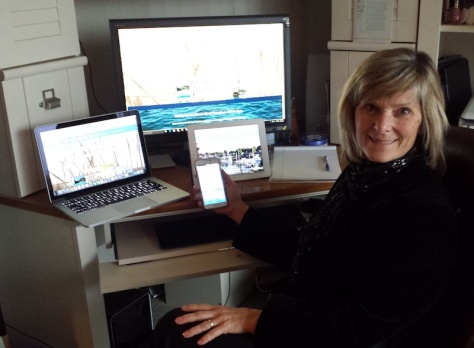 Photo of Cheri Calvert with a Windows desktop, Apple Notebook, Tablet, and Android phone.